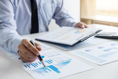 Midsection of businessman working over graph on table