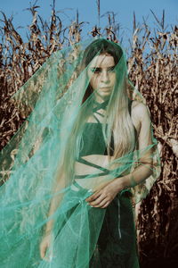 Portrait of woman covered in netting while standing against plants