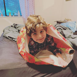 Portrait of cute boy lying on bed at home