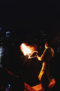Man standing by fire burning at night