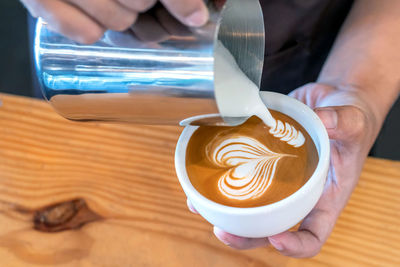 Midsection of woman holding coffee cup on table