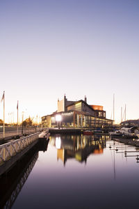 Illuminated the gothenburg opera reflection in water at harbor against clear purple sky