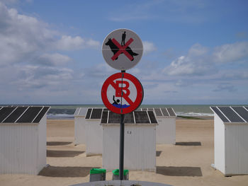 Information sign on beach against sky