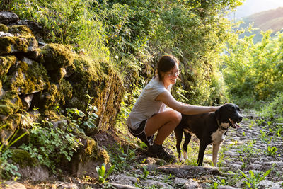 Woman petting and playing with her dog in a forest.