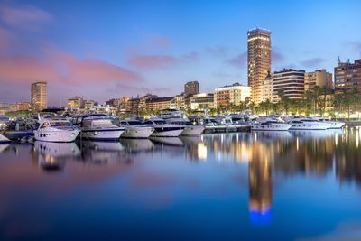 Boats moored at harbor against buildings in city