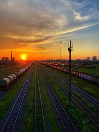 Railroad tracks on field against sky during sunset