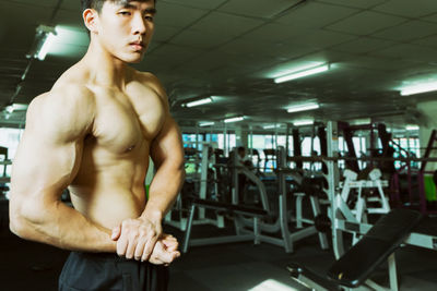 Shirtless muscular man flexing muscles at gym