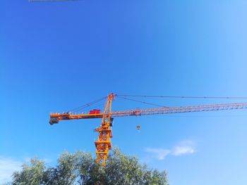 Low angle view of crane against clear blue sky