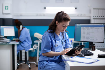 Young woman using laptop while standing in office