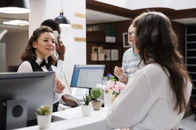 Portrait of young woman using laptop while standing in office