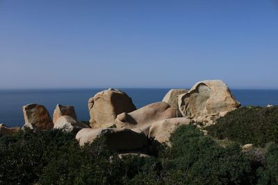 Rocks on beach against clear sky