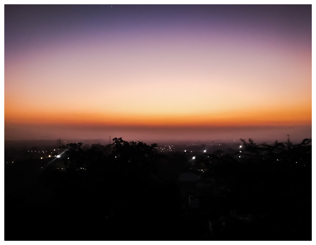 SILHOUETTE CITY BY SEA AGAINST SKY AT SUNSET