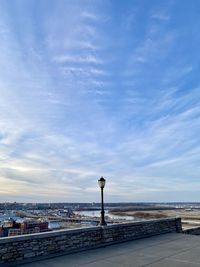 Street light by river against sky