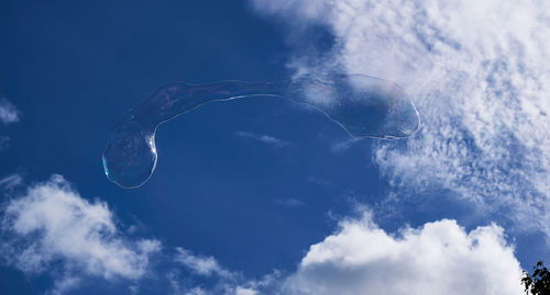 Low angle view of bubbles against blue sky