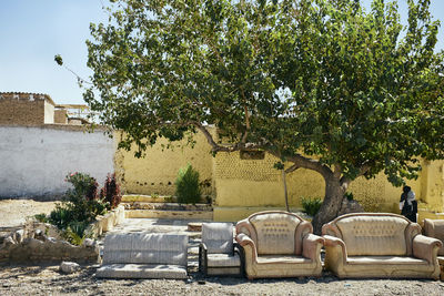 Empty chairs by footpath against buildings in city