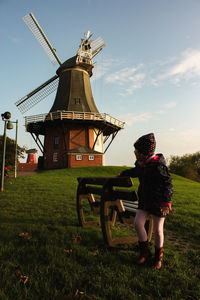 Full length of traditional windmill on field against sky