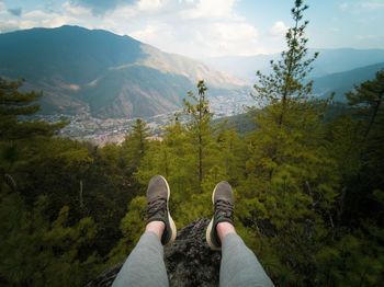 Low section of person on mountain against sky