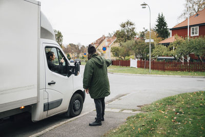 Man directing woman sitting in delivery van on street