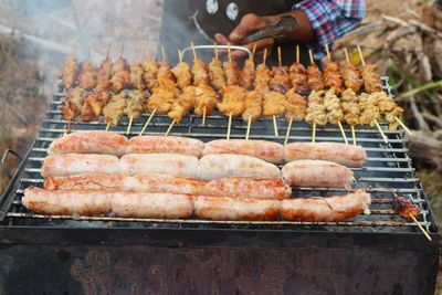 Midsection of woman roasting meat on barbecue grill