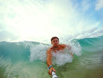 Portrait of shirtless man swimming at sea against sky