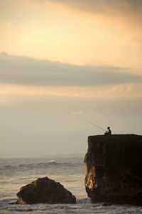 Rock formations by sea against sky during sunset