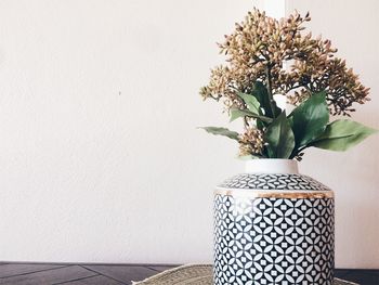 Close-up of white flower vase on table against wall