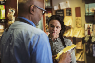 Owner showing food label to customer at store