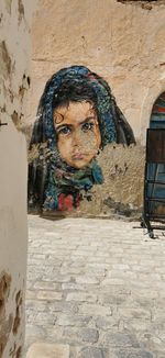 Portrait of boy sitting on wall against building