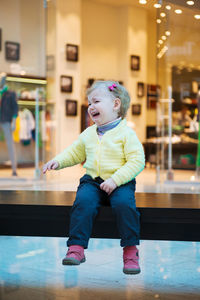 Cute girl crying while sitting at mall