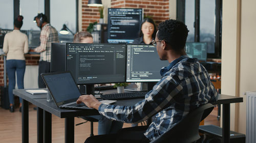 Rear view of computer programmer working at office