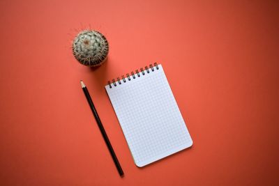 High angle view of clock on paper against orange background