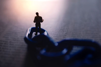 Close-up of silhouette figurine on metal during sunset