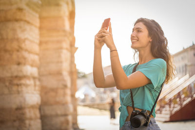 Smiling young woman taking selfie in city