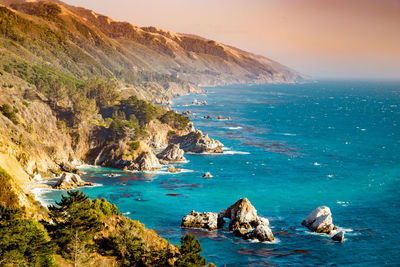 Scenic view of sea by mountains against sky