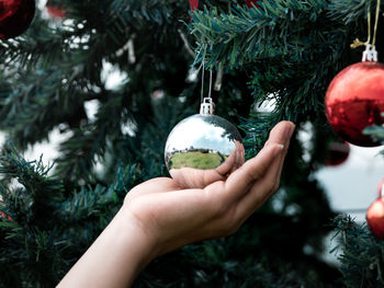 Close up of hand holding on christmas baubles, balls on christmas tree branch.  merry christmas.