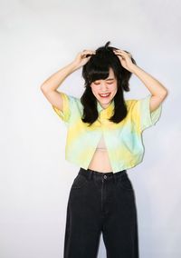 Portrait of young woman standing against white background