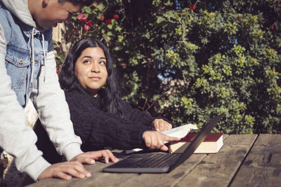 Two young men study outside school with laptops