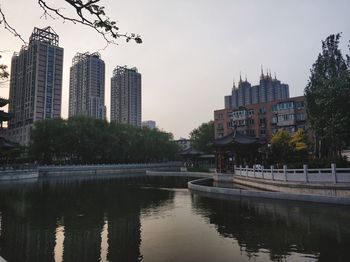 City buildings by river against sky