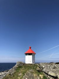 Lighthouse by sea against clear sky