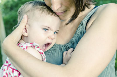 Midsection of mother carrying baby girl