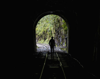 Rear view of silhouette person standing in tunnel