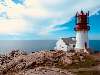 Lighthouse by sea against sky