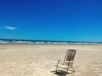 Lifeguard chair on beach against clear blue sky