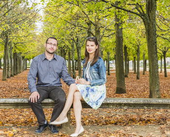 Full length of young couple sitting on bench at park