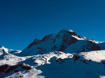 Scenic view of snowcapped mountains against clear blue sky