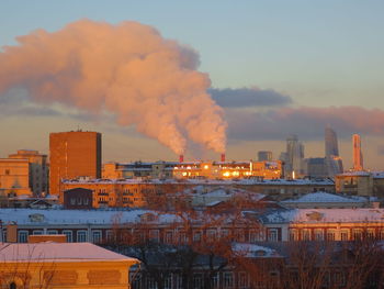 Smoke emitting from factory against sky