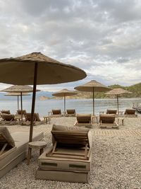 Lounge chairs and parasols on beach against sky