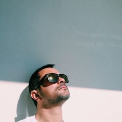 Portrait of young man wearing sunglasses against wall