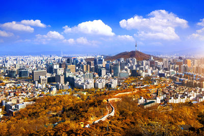 Distant view of n seoul tower on namsan mountain amidst cityscape against sky