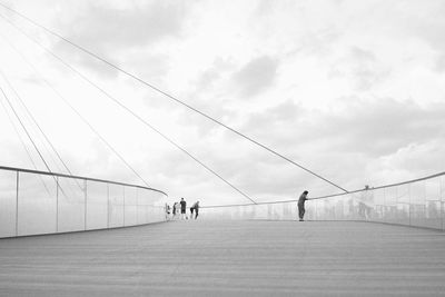 People walking on bridge against sky